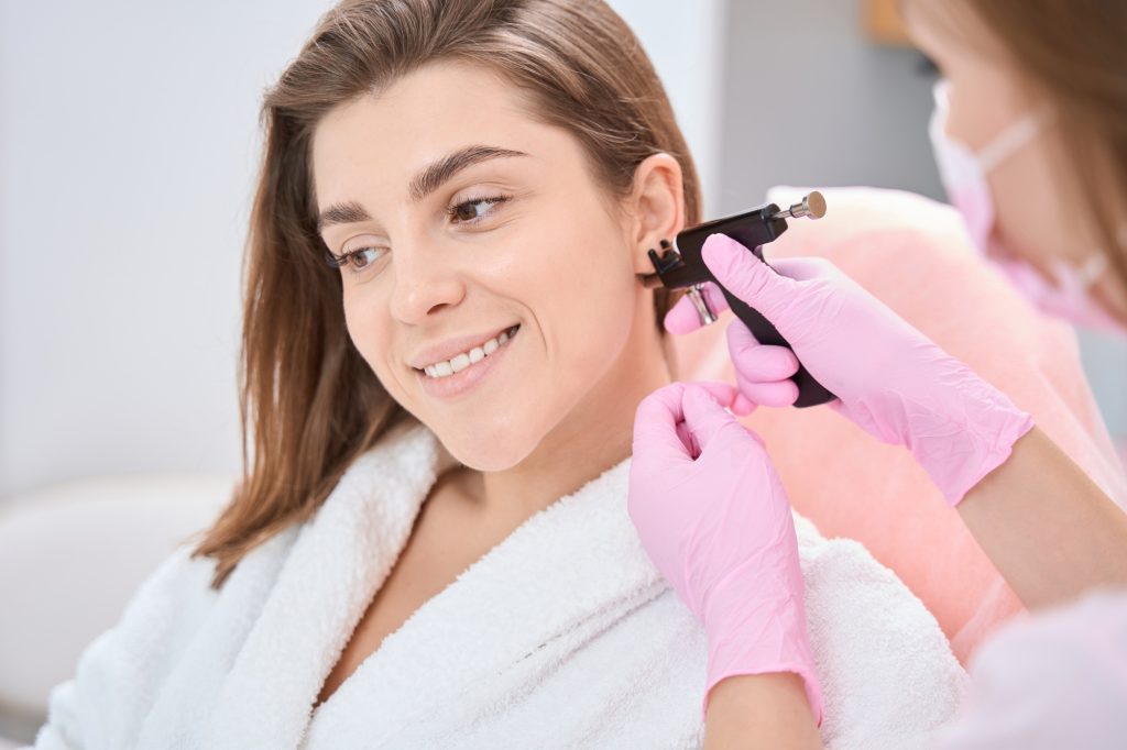 Woman is putting an ear piercing machine to her ear