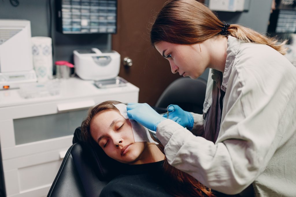Young woman doing ear piercing at beauty studio salon.