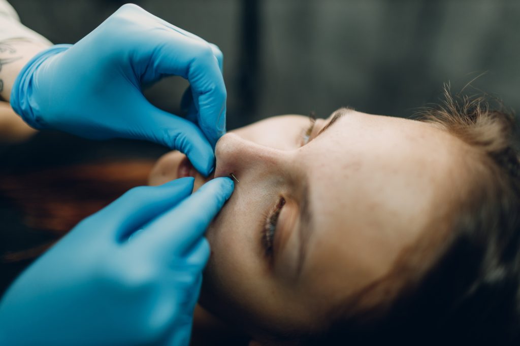 Young woman doing piercing at beauty studio salon.