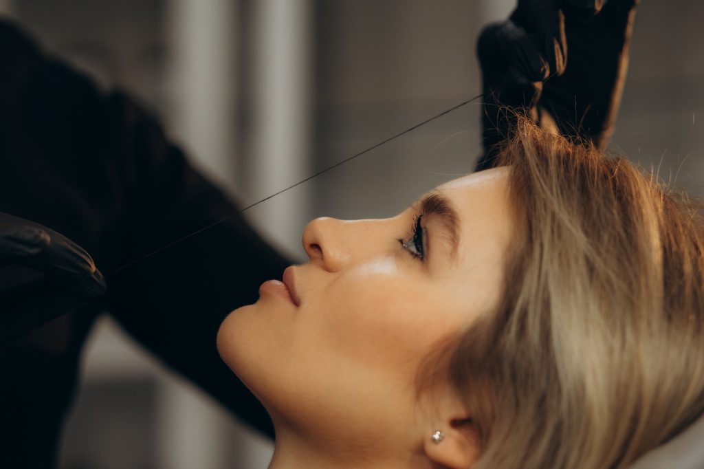 Grooming the eyebrows thread in a beauty salon. close