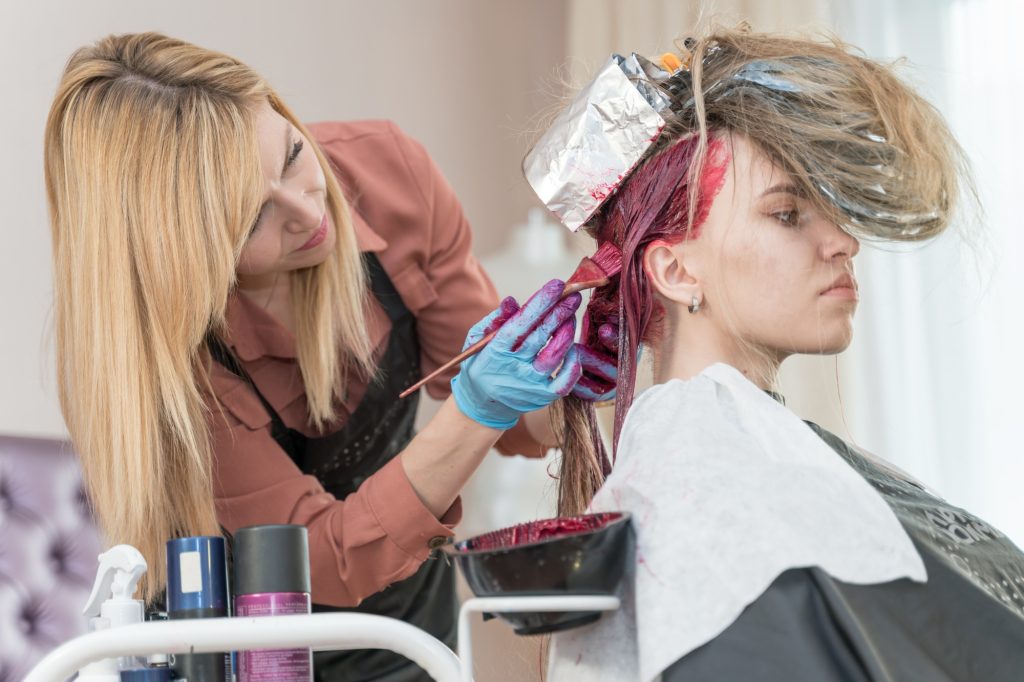 hairdresser makes hair coloring to young girl